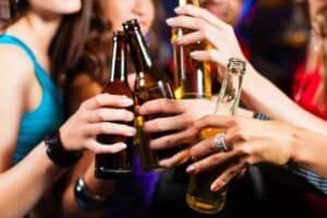 Group of party people - men and women - drinking beer in a pub