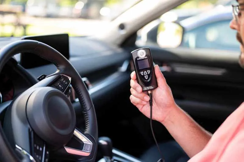 Man holding LifeSafer ignition interlock device in his car