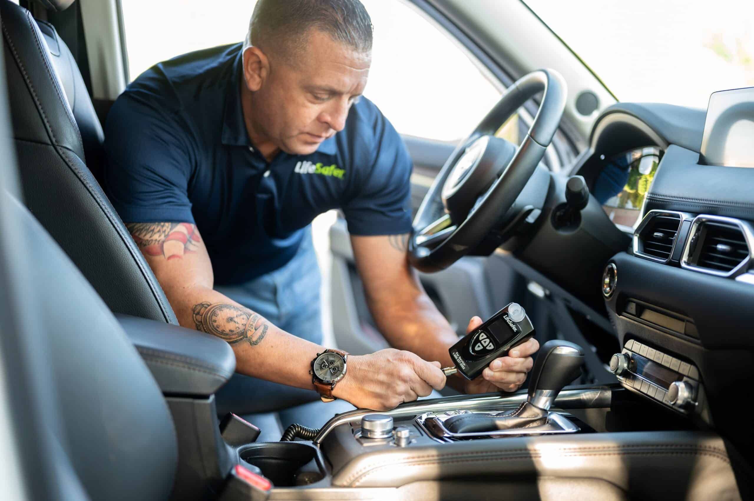Image of Lifesafer technician carefully installing and calibrating an ignition interlock device during a mobile installation.